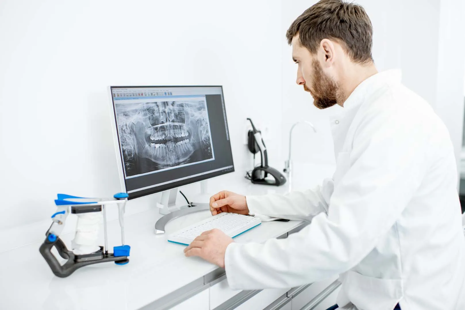 Clinician reviewing a digital dental scan beside a 3D scanner